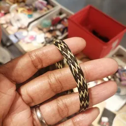 Close-up van een goudkleurige armband met gevlochten patroon om iemands pols