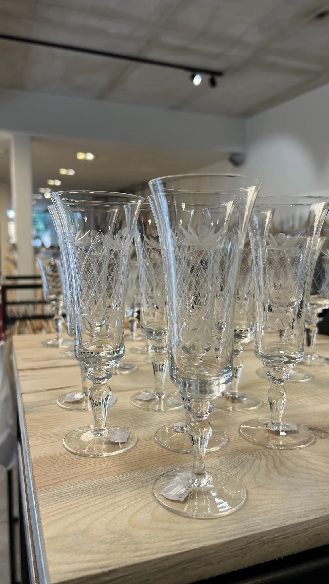 Zes kristallen glazen met geslepen patroon, staande op een houten tafel
