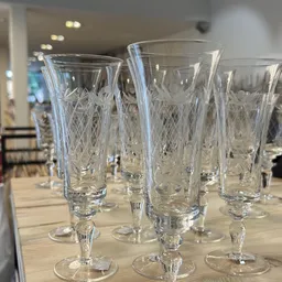 Zes kristallen glazen met geslepen patroon, staande op een houten tafel