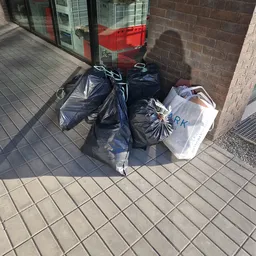 Vuilniszakken en een witte plastic krat op de tegel voor een winkel
