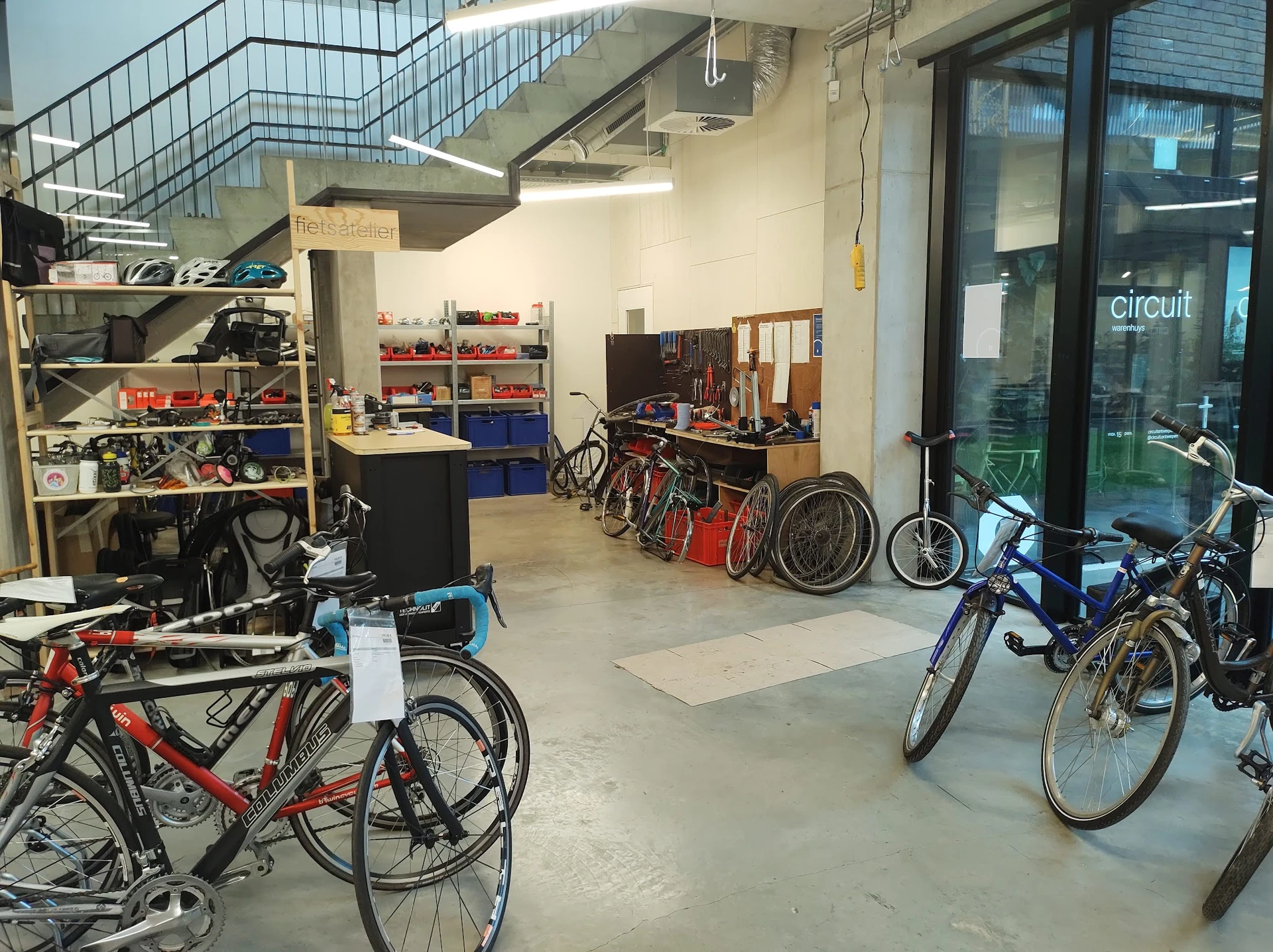 Werkplaats met fietsreparatie-stellingen, gereedschap en verschillende fietsen in verschillende stadia van restauratie