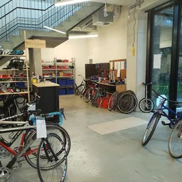 Werkplaats met fietsreparatie-stellingen, gereedschap en verschillende fietsen in verschillende stadia van restauratie