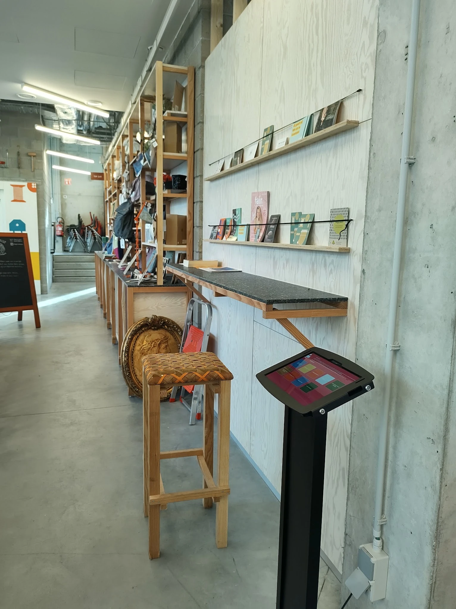 Winkelinterieur met houten werkbank, kruk, boekenplank en displaystandaard met kleurrijke tegels