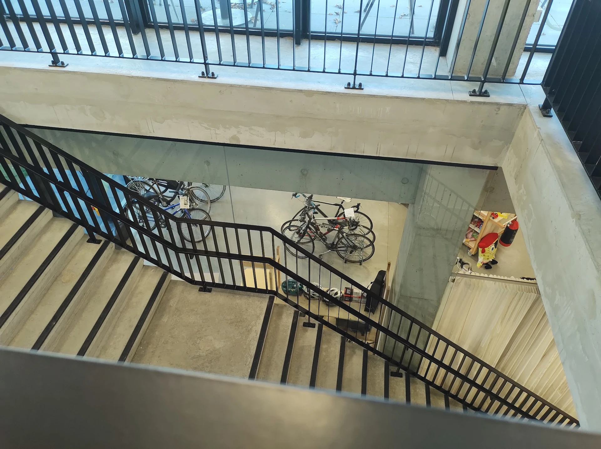 Trap met zwart hekwerk en fietsen in een trappenhuis van de winkel