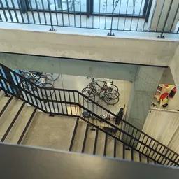 Trap met zwart hekwerk en fietsen in een trappenhuis van de winkel