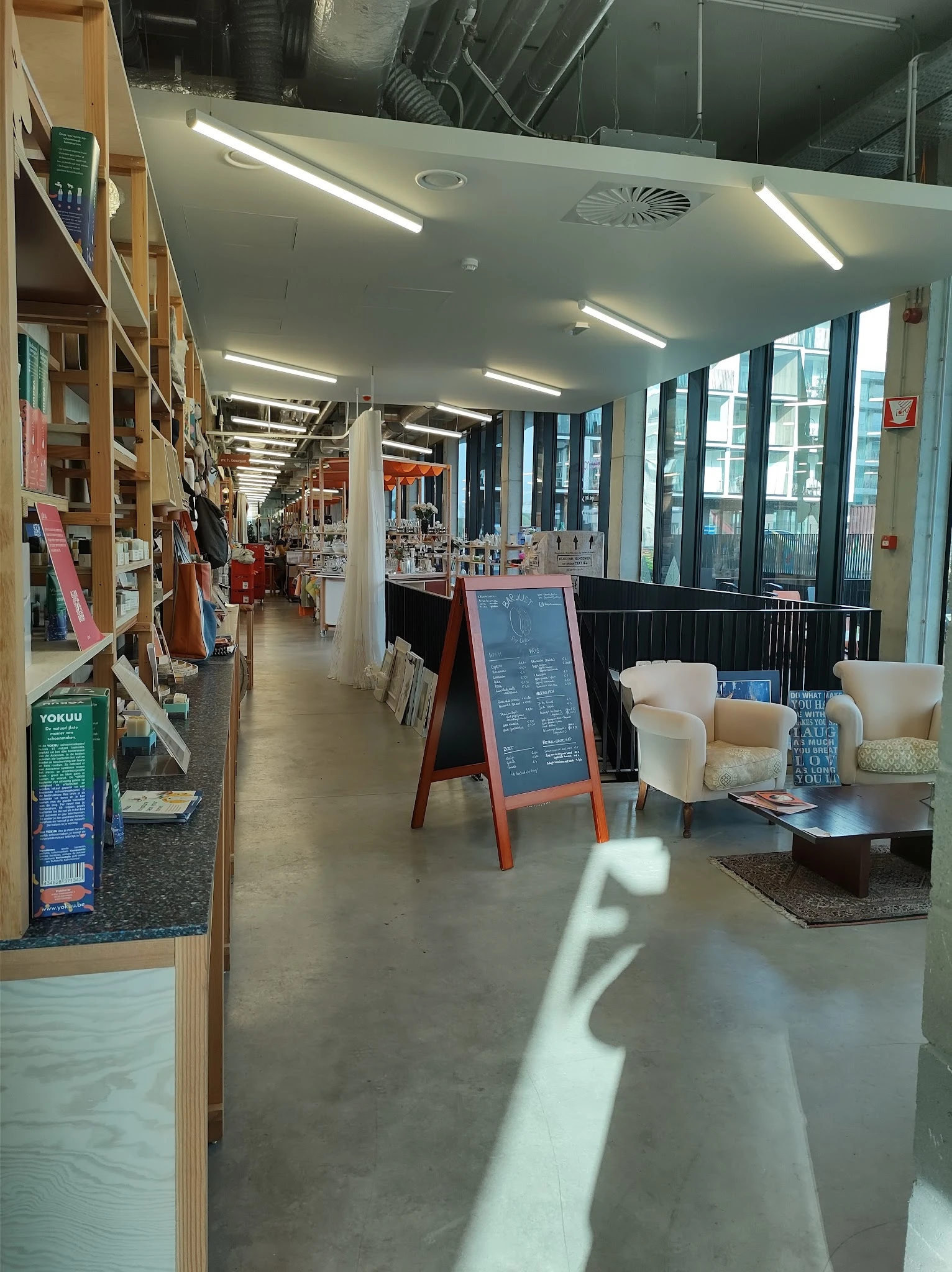 Winkelinterieur met boekenkasten links, zithoeken met stoelen en een menubord in het midden