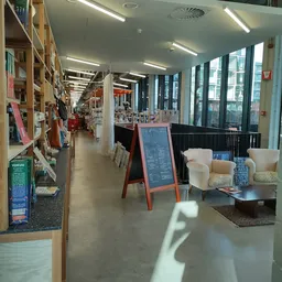 Winkelinterieur met boekenkasten links, zithoeken met stoelen en een menubord in het midden