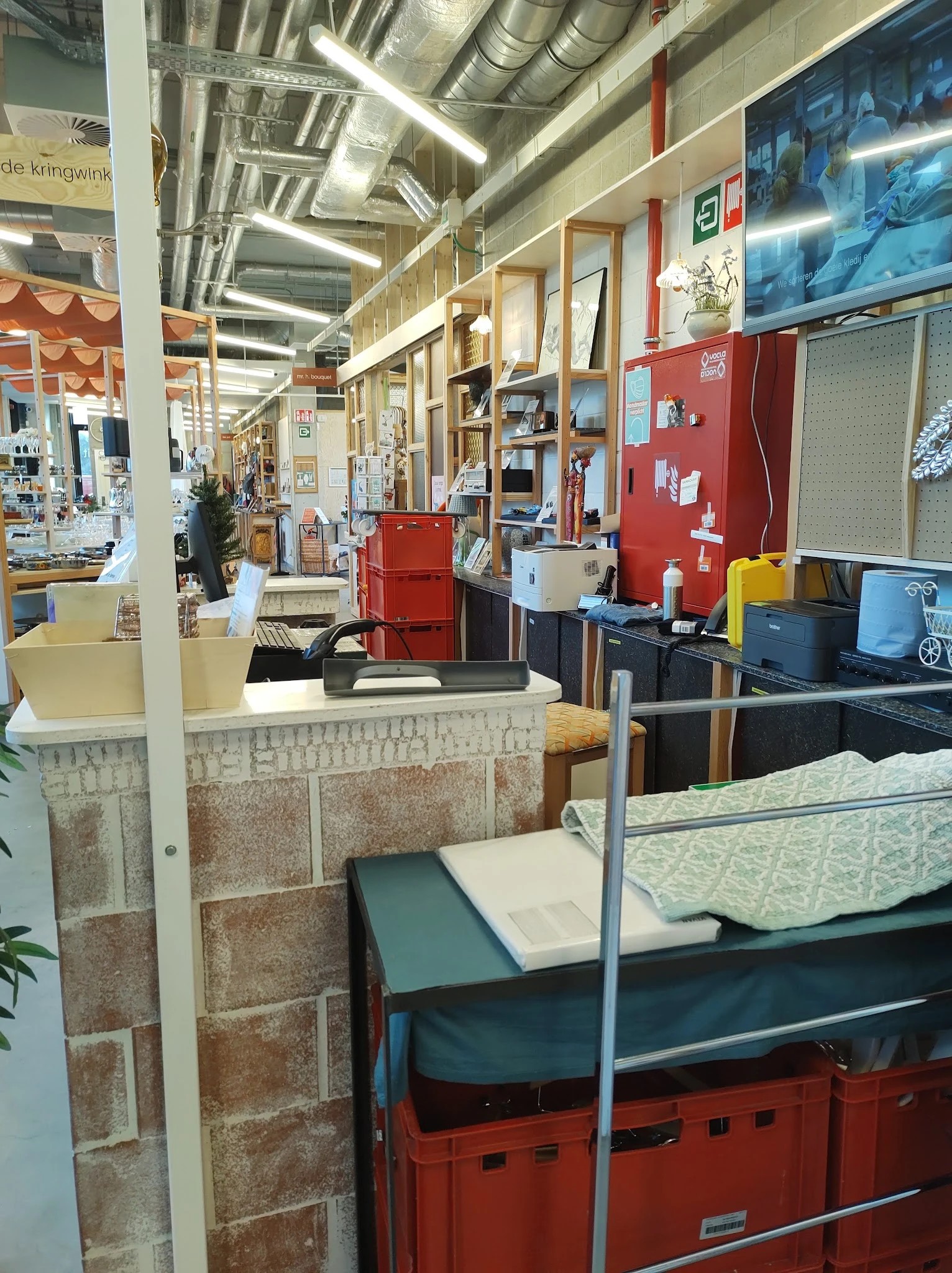 Winkelvloer met stellingen, toonbanken en uitgestalde spullen in een kringloopwinkel