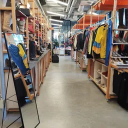 Winkelpad met houten kledingrekken aan weerszijden, volgehangen met tweedehands kleding in verschillende kleuren