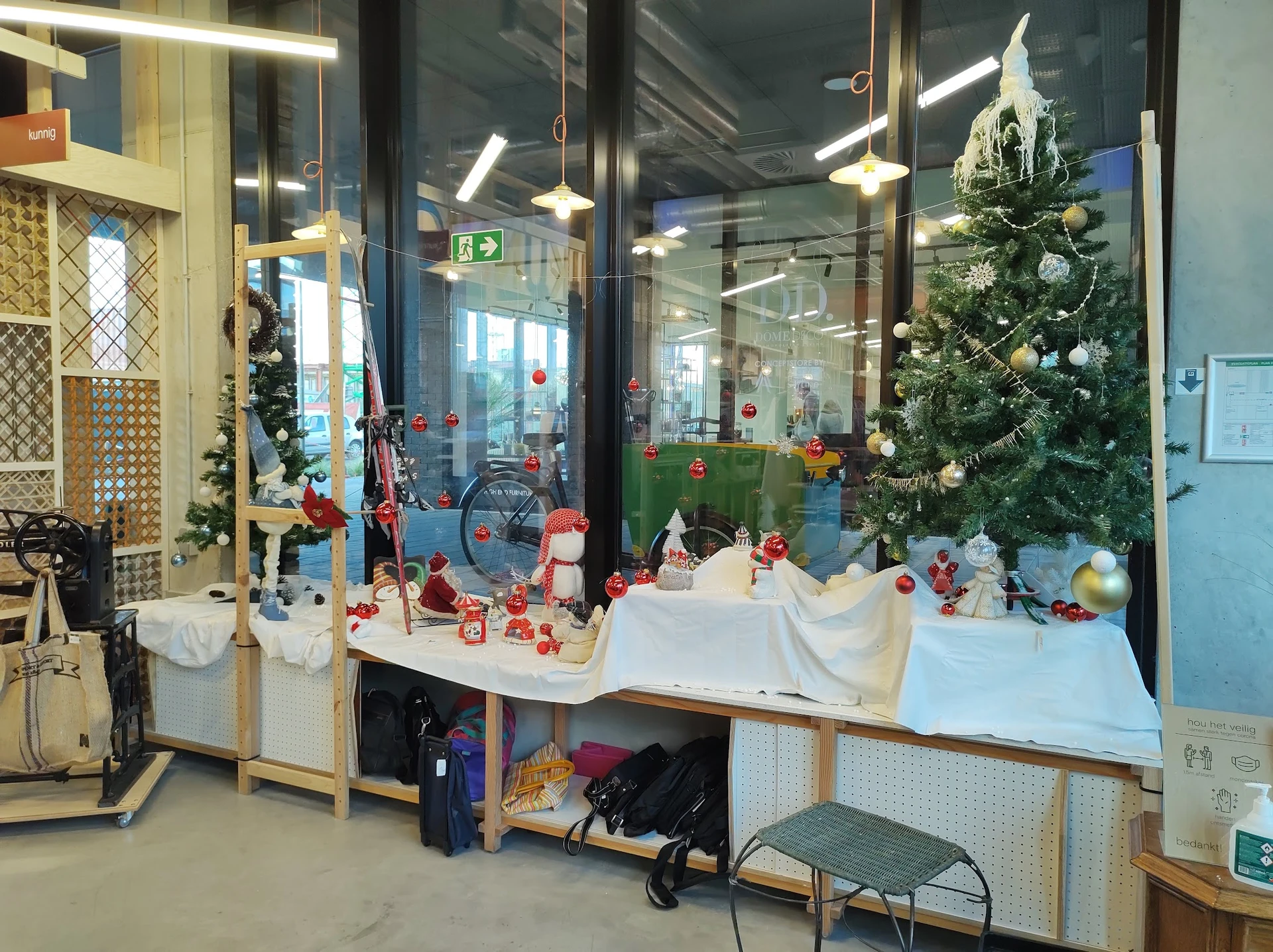 Winkelraam met kerstdecoratie, speelgoed en artikelen op display, kerstboom met verlichting zichtbaar