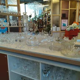 Grote verzameling kristalwerk en glazen servies uitgestald op een toonbank in de winkel