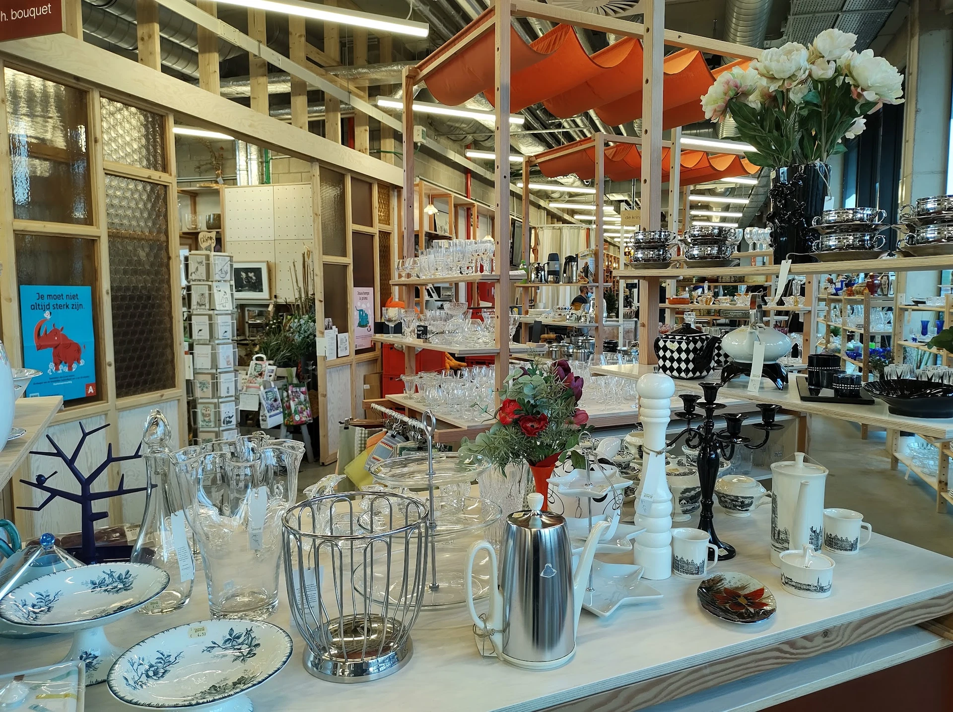 Uitgestalde huishoudartikelen en decoratie: servies, glazen, kandelaars, bloemen en diversen