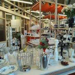 Uitgestalde huishoudartikelen en decoratie: servies, glazen, kandelaars, bloemen en diversen