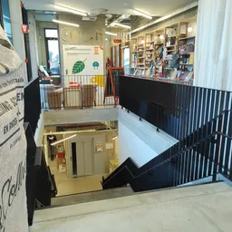 Overzicht van twee verdiepingen in een kringloopwinkel met trappen, zwarte balustrades en boekenkasten
