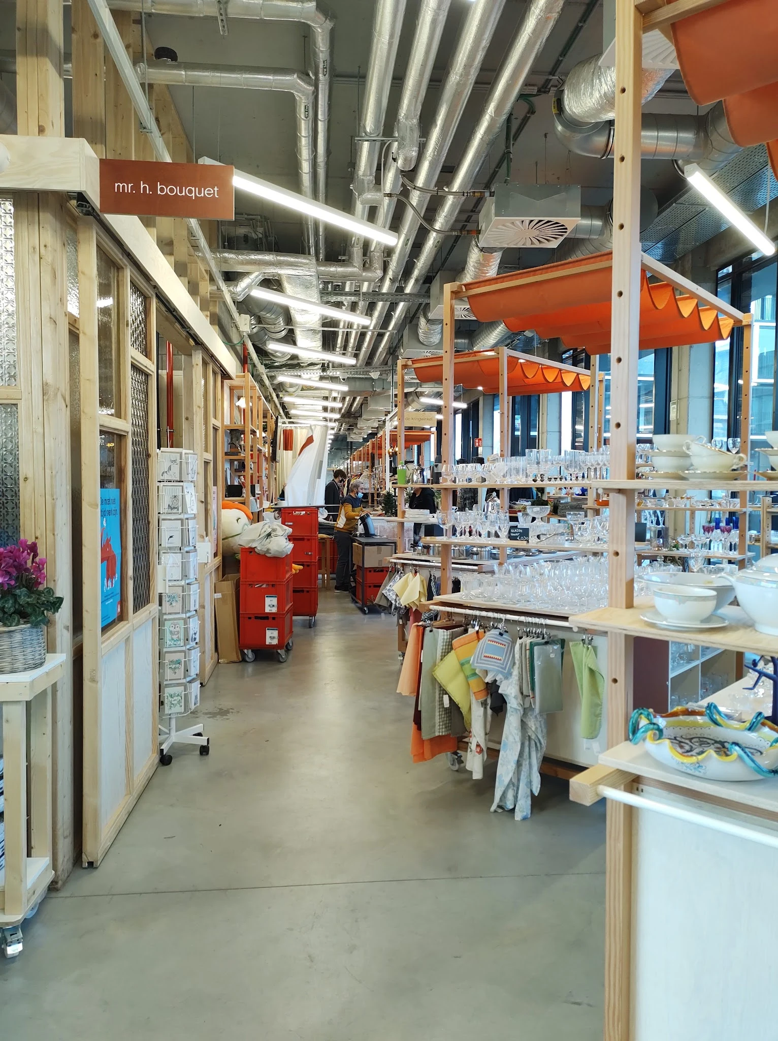 Binnenaanzicht van kringloopwinkel met stellingen, rekken met spullen en oranje parasols als decoratie