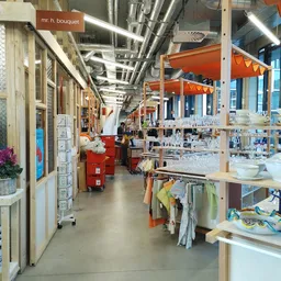 Binnenaanzicht van kringloopwinkel met stellingen, rekken met spullen en oranje parasols als decoratie