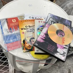 Verzameling dvd's en films op een tafel, waaronder titels als 'Storytelling', 'O Brother', 'Capote' en 'The Darwin Project'