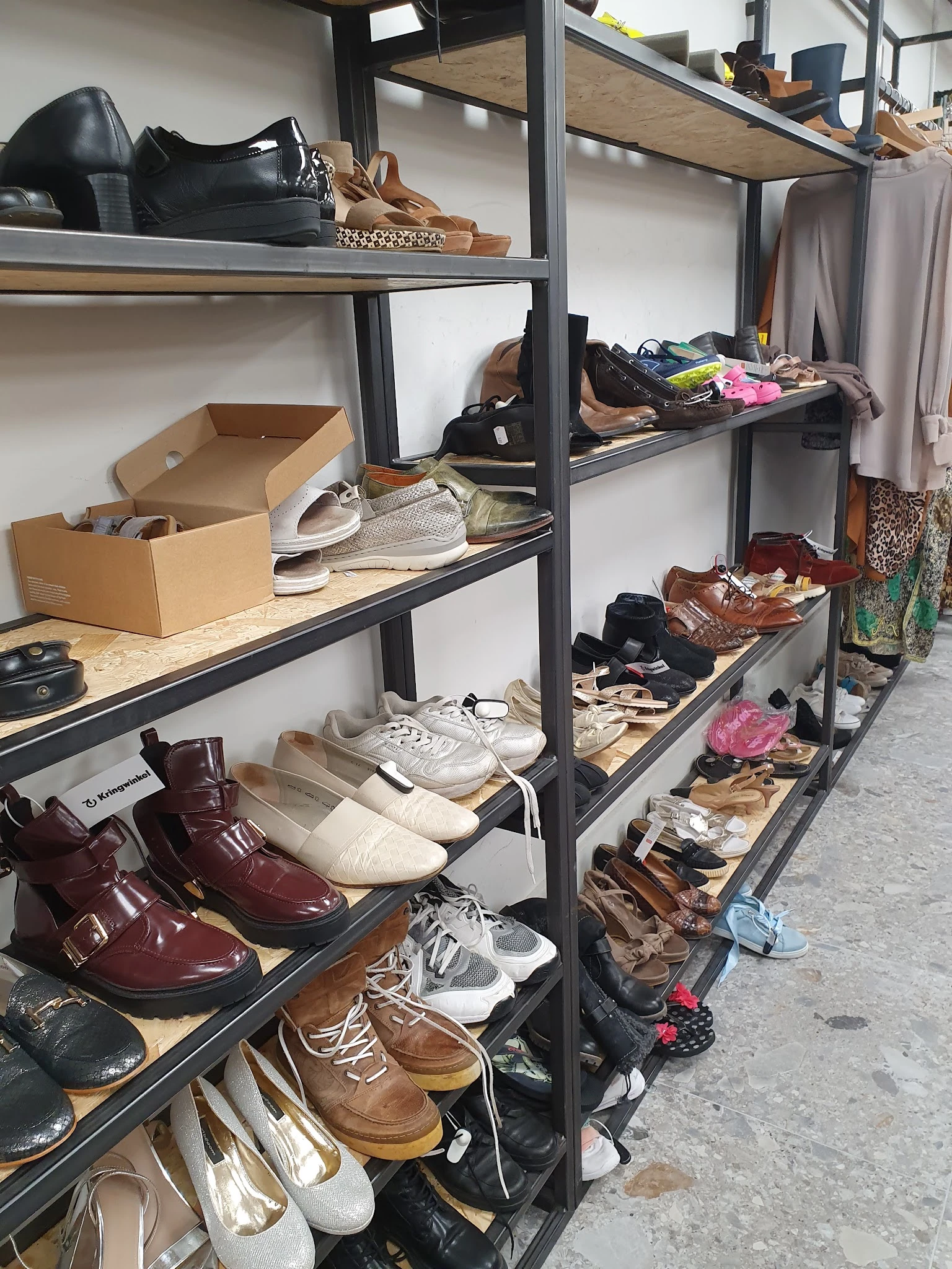 Metalen stellingen met uitgestalde tweedehands schoenen en footwear in verschillende kleuren en stijlen