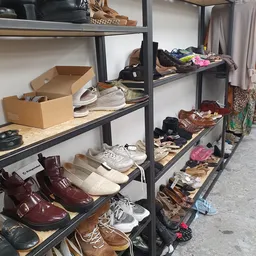 Metalen stellingen met uitgestalde tweedehands schoenen en footwear in verschillende kleuren en stijlen