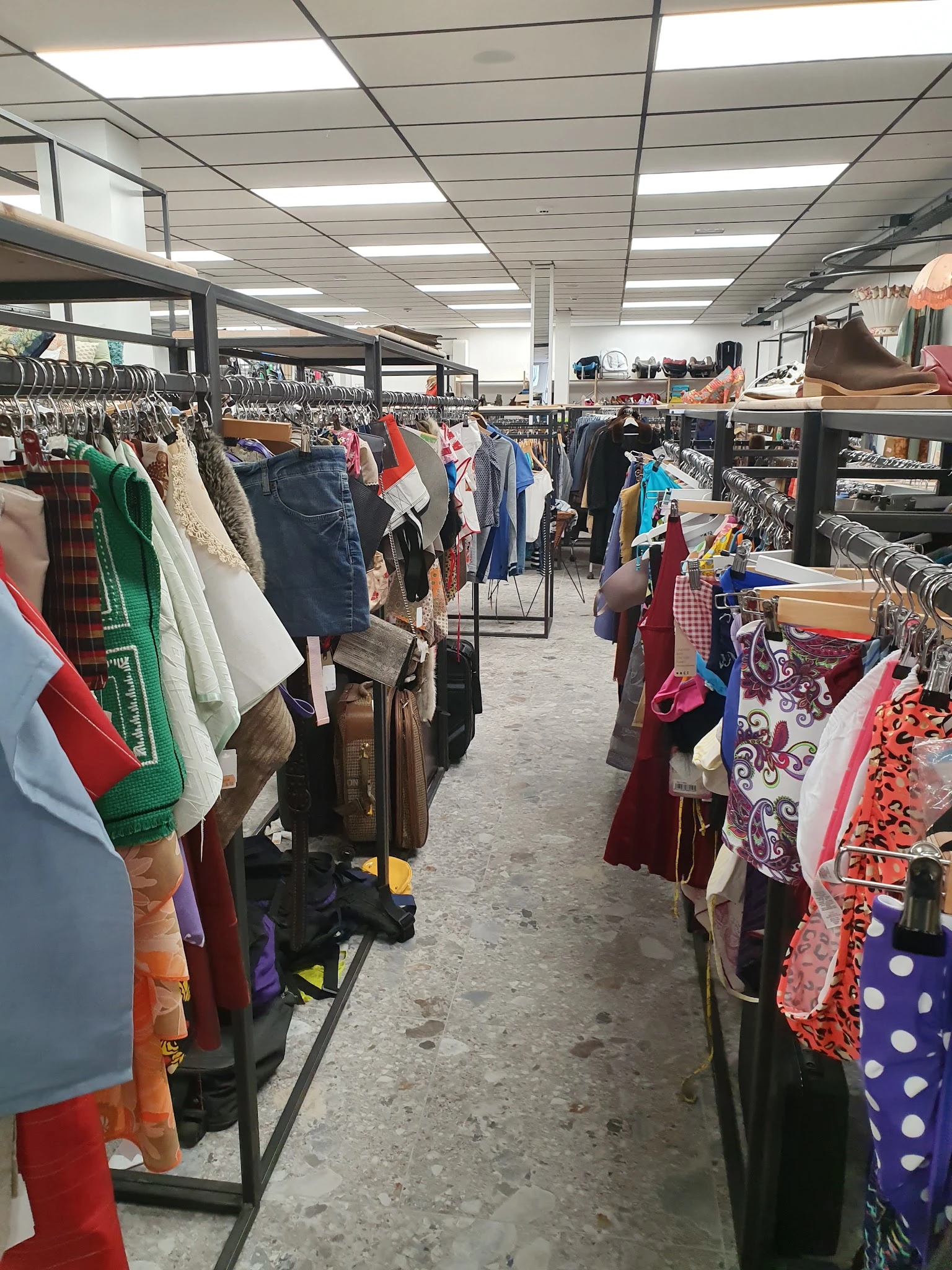 Winkelvloer met rekken vol tweedehands kleding, tassen en accessoires