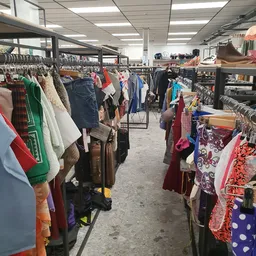 Winkelvloer met rekken vol tweedehands kleding, tassen en accessoires