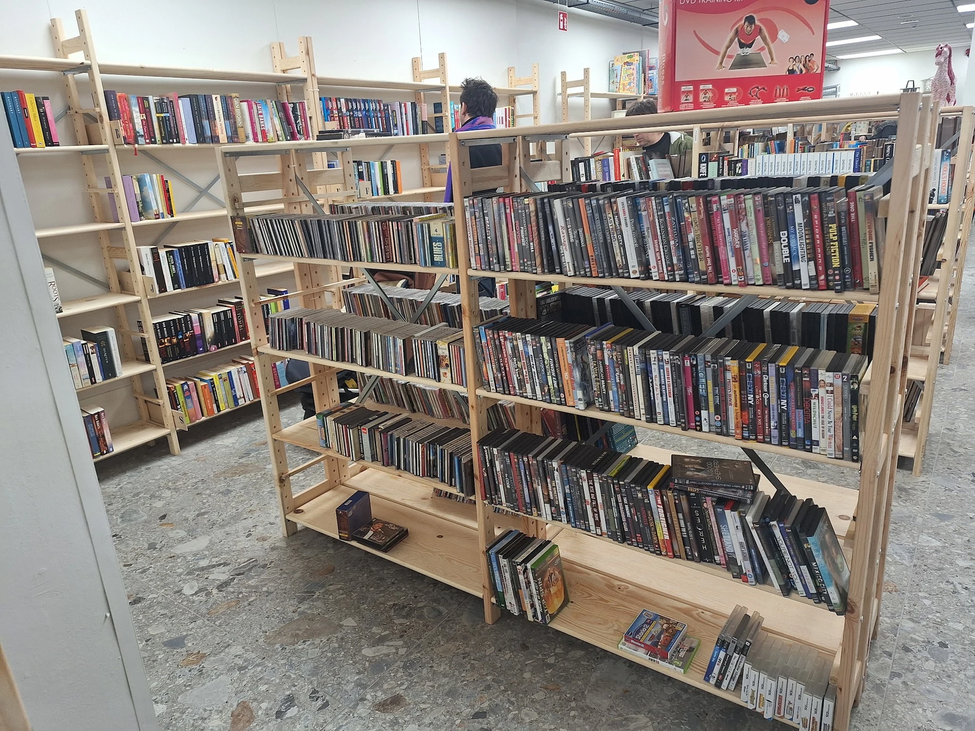 Houten stellingen met tweedehands dvd's en blu-rays, georganiseerd op meerdere niveaus