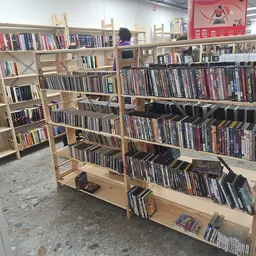 Houten stellingen met tweedehands dvd's en blu-rays, georganiseerd op meerdere niveaus