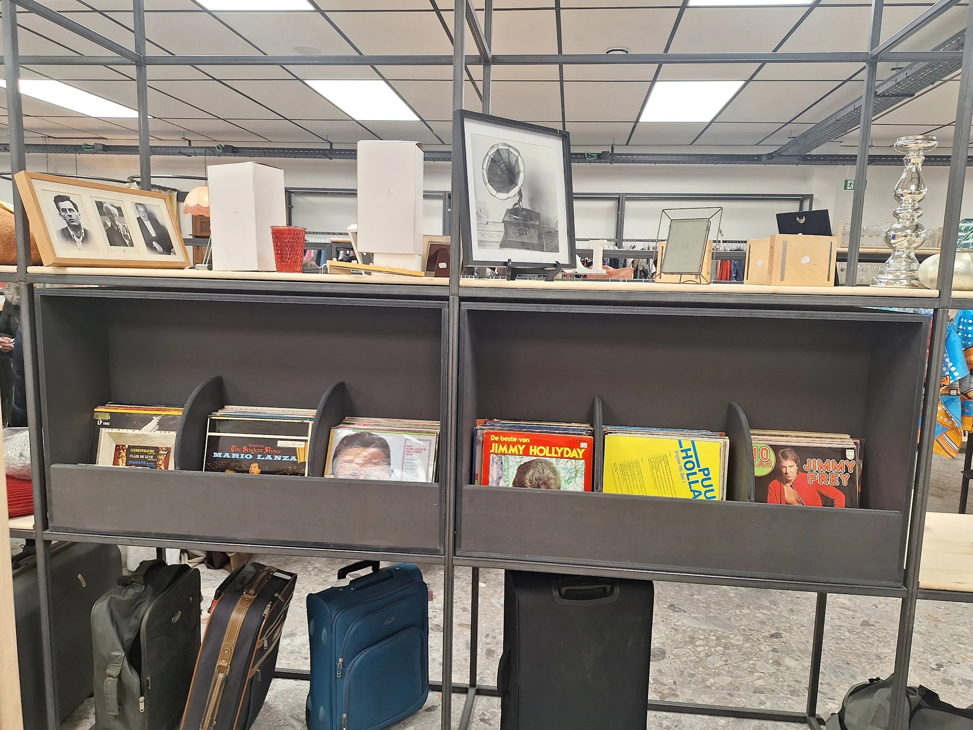 Grijze stellingen met cd's, vinyl, boeken en ander media in een kringloopwinkel