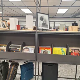Grijze stellingen met cd's, vinyl, boeken en ander media in een kringloopwinkel