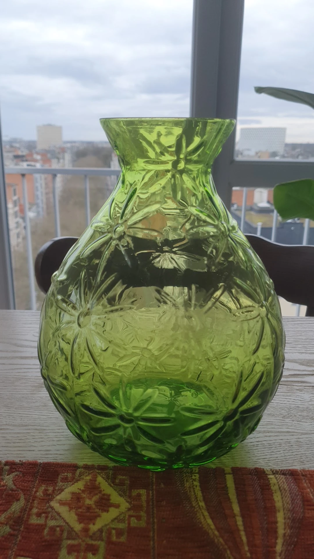 Close-up van een groen gereliefd glazen kan of karaf met bloemmotieven