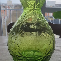 Close-up van een groen gereliefd glazen kan of karaf met bloemmotieven