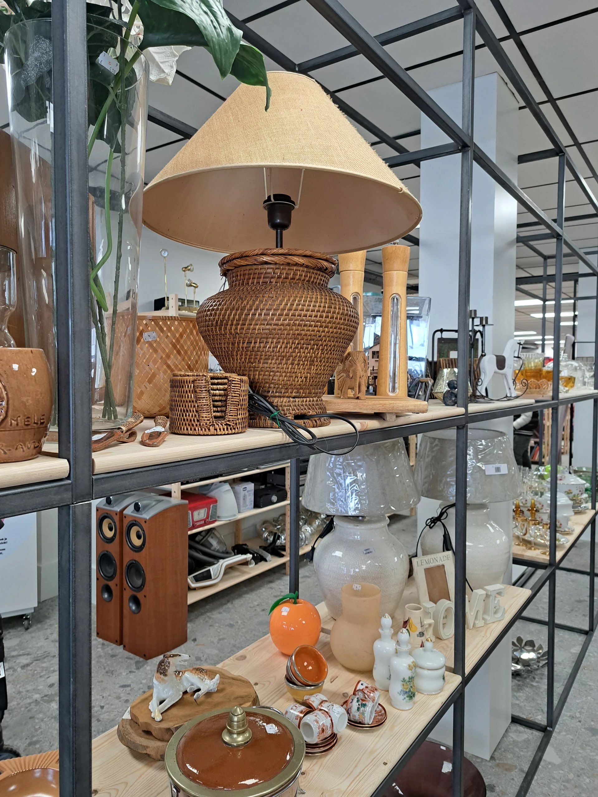 Expositie van rieten manden, lampenkappen en houten huishoudartikelen op een stellingkast