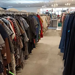 Rekken met tweedehands kleding, waaronder jassen, jasjes en truien in verschillende kleuren en patronen