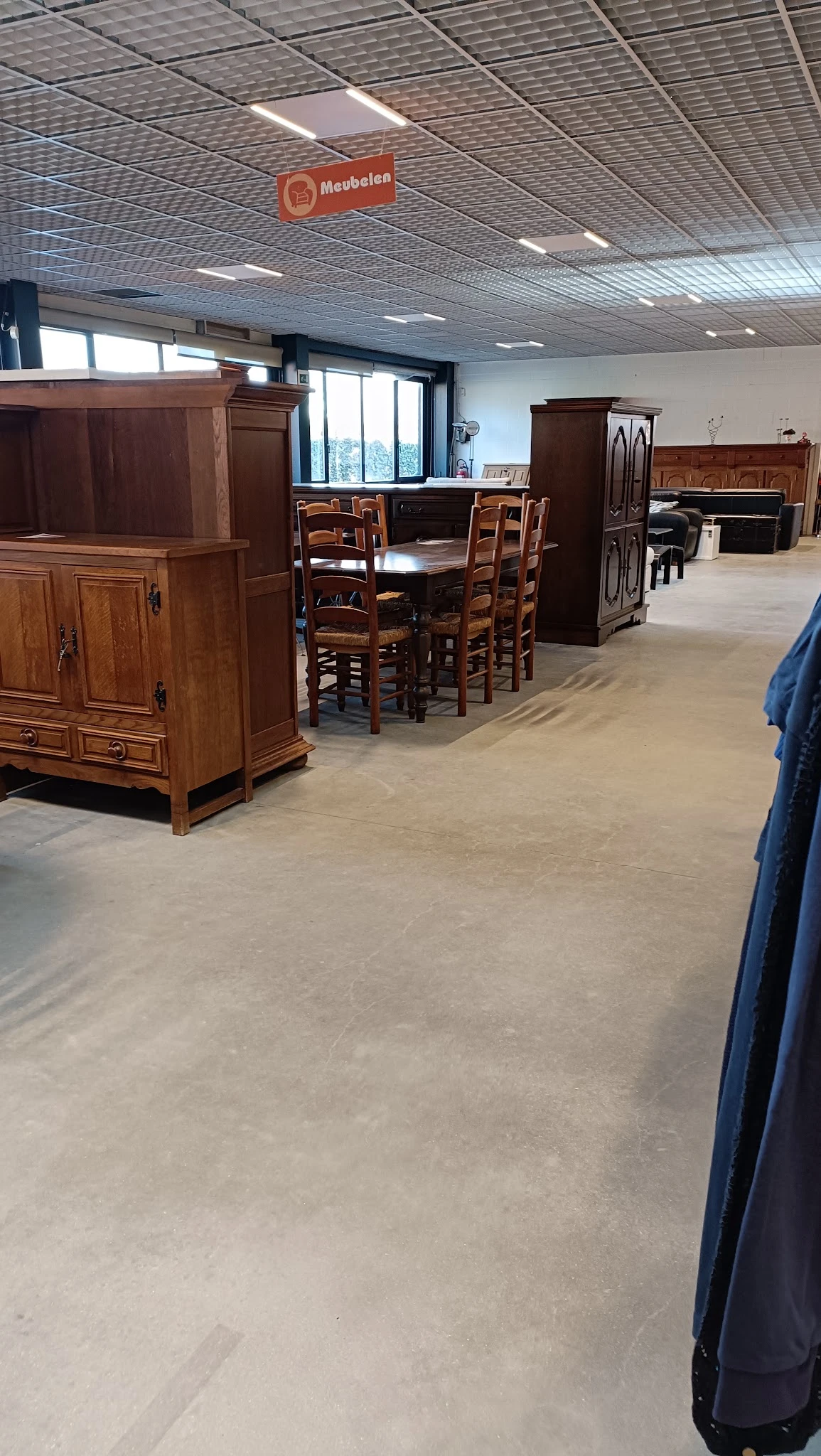 Winkelinterieur met houten meubels, eettafel met stoelen en houten kasten, betonnen vloer
