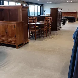 Winkelinterieur met houten meubels, eettafel met stoelen en houten kasten, betonnen vloer