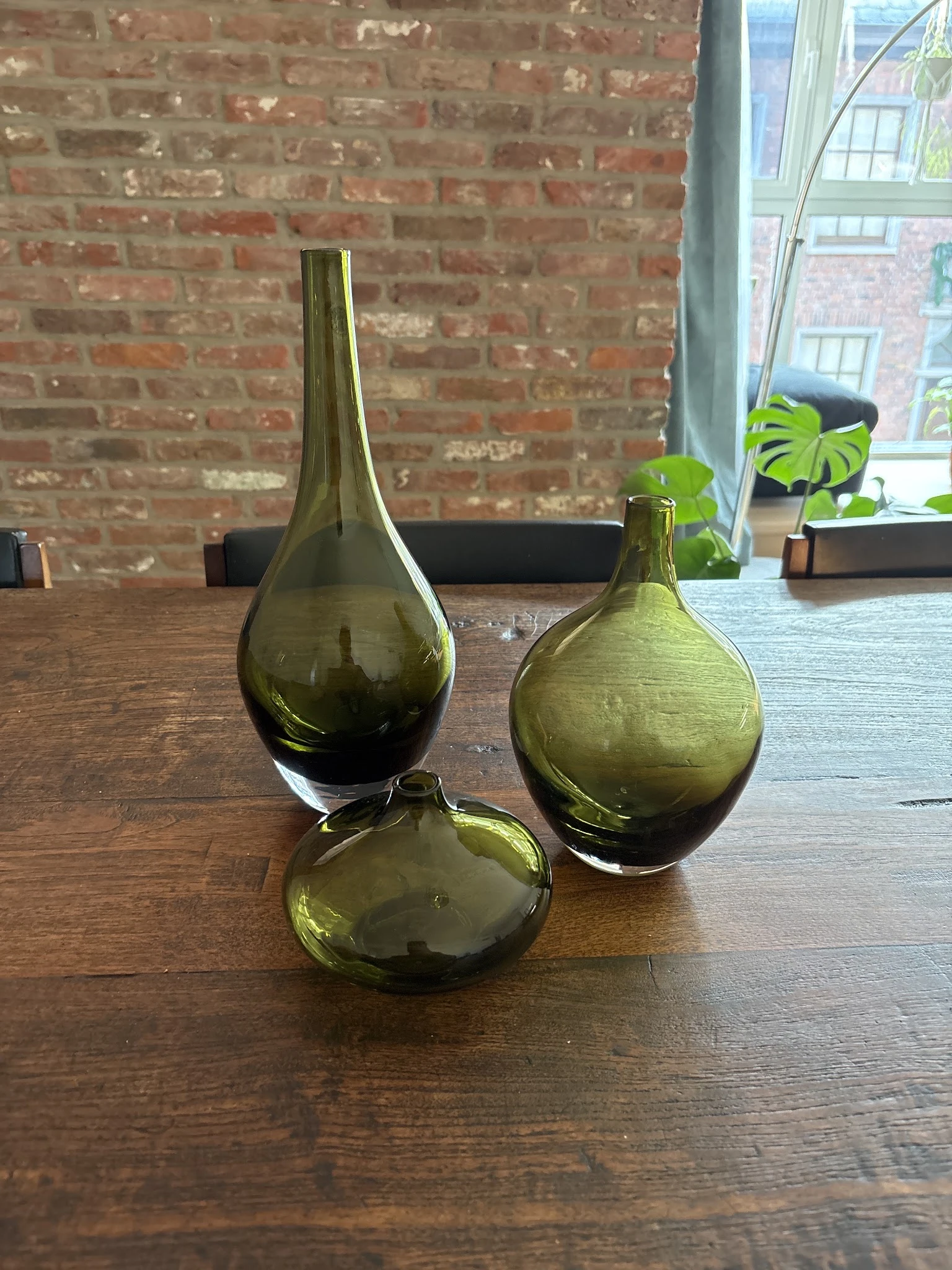 Drie groene glazen flesjes in verschillende vormen op houten tafel