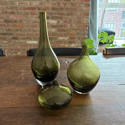 Drie groene glazen flesjes in verschillende vormen op houten tafel