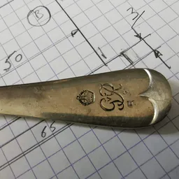 Close-up van een antieke messing lepel met gravering op ruitjespapier met aantekeningen
