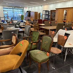 Uiteenlopende tweedehands meubels en stoelen met oranje prijskaartjes in de winkel