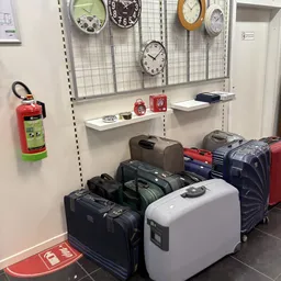 Verschillende koffers en tassen uitgestald op de winkelbodem en op stellingen, met een klok boven