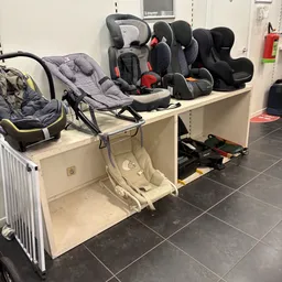 Uitgestalde kinderzitjes, autostoeltjes en een kinderwagen in een kringloopwinkel