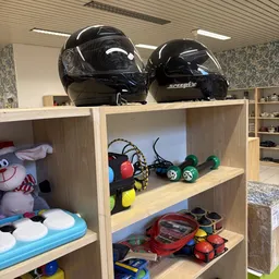 Houten stellingkast met uitgestalde gebruikte spullen: helmen, rolschaatsen, speelgoed en sportartikelen