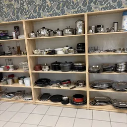 Houten stellingen vol met pannen, potten, servies en keukenartikelen
