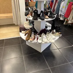 Twee witte displaypiramides met uitgestalde tweedehands schoenen en sneakers in verschillende kleuren en stijlen