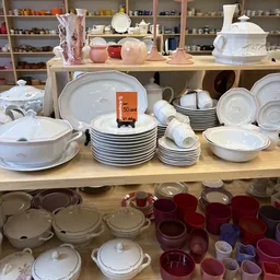 Uitgestalde serviesgoed: stapels witte borden, schalen en kopjes in een kringloopwinkel