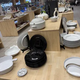 Uitgestalde serviesgoed en borden in zwart en wit op houten tafels in de winkel