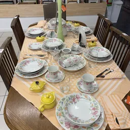 Gedekte tafel met servies met bloemmotief, gele theepotten en bestek