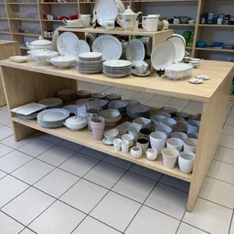 Houten stellingkast met witgoed servies, borden, kopjes en huishoudelijke items uitgestald