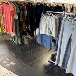 Rekken met tweedehands kleding: jassen, broeken en spijkerbroeken in verschillende kleuren