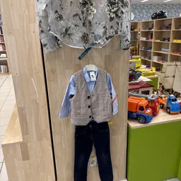 Kinderoutfit op etalagepop: grijs geblokt jasje met blauwe overhemd en donkerblauwe broek